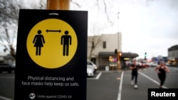 FILE - People jog past a social distancing and mask-wearing sign, in Auckland, New Zealand, Aug. 31, 2020. New Zealand announced on Aug. 14, 2023, that it was removing the last of its remaining COVID-19 restrictions.