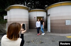 Turis asing berfoto di depan toilet umum yang didesain ulang sebagai bagian dari proyek mengubah toilet umum menjadi toilet yang dapat digunakan dengan nyaman oleh semua orang, di kawasan Shibuya, di Tokyo, Jepang April 4, 2024. (REUTERS/Kim Kyung-Hoon)