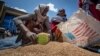 FILE - An Ethiopian woman scoops up portions of wheat to be allocated to each waiting family in the Tigray region of northern Ethiopia on May 8, 2021. The U.N. World Food Program is slowly resuming food aid to Ethiopia, the agency said on Aug. 9, 2023.