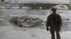 A NATO soldier stands at the site of a suicide car bomb blast in Kabul, Afghanistan, Oct. 11, 2015.