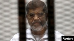 FILE - Ousted Egyptian President Mohamed Mursi is seen behind bars during his trial at a court in Cairo, May 8, 2014. 