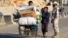 A civilian with his belongings walks past a Free Syrian Army fighter at the Syrian border crossing of Bab al-Hawa, at the Syrian-Turkish border, Oct. 22, 2013.