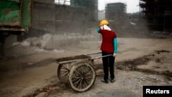 上海建築工地前站著一名女農民工（資料照片）