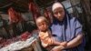 A Somali woman selling meat from a kiosk holds her child in a market area in the centre of the southern port city of Kismayo, south of Mogadishu, October 7, 2012 
