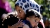 Syrian refugee girl carries her sister, at camp in Ketermaya village, southeast of Beirut, March 14, 2013.