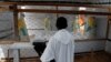 FILE - A priest watches as health workers dressed in Ebola protective suits prepare the body of an Ebola patient for burial at the Ebola treatment center in Butembo, in the Democratic Republic of Congo, March 26, 2019. 