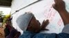 A child writes a note to former South African President Nelson Mandela on a banner at the Nelson Mandela Museum in Qunu, Dec. 12, 2013.