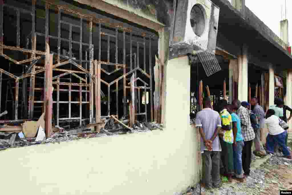 Mahalliy aholi vakillari Mpeketonida jangarilar vayron qilgan binolarni ko'zdan kechirmoqda, 16-iyun, 2014-yil.