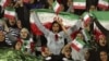 FILE - In this Oct. 16, 2018 file photo, Iranian women cheer as they wave their country's flag after authorities in a rare move allowed a select group of women into Azadi stadium to watch a friendly soccer match between Iran and Bolivia, in Tehran, Iran. 