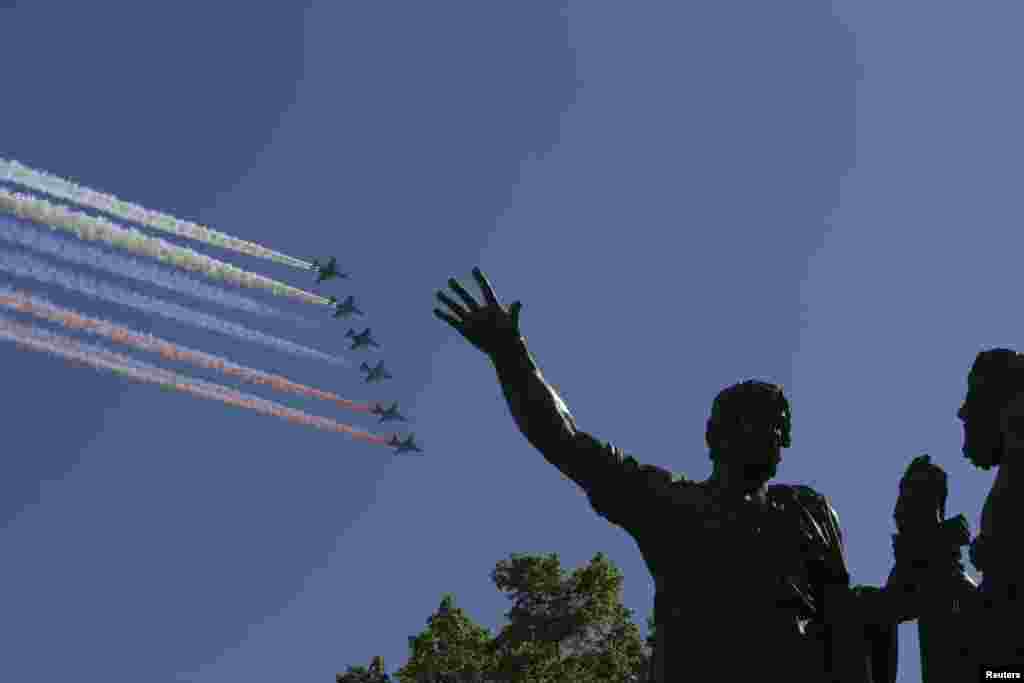 Russian military aircraft trail smoke in the colours of the Russian tricolor above the Monument to Minin and Pozharsky during the Victory Day Parade in Moscow's Red Square, May 9, 2014.