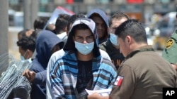 Oficiales de la Patrulla Fronteriza de Estados Unidos devuelven a un grupo de migrantes de regreso al lado mexicano de la frontera, mientras los funcionarios de inmigración revisan la lista en Nuevo Laredo.