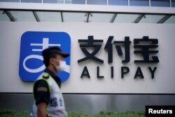 Seorang penjaga keamanan berjalan melewati logo Alipay di kantor Alipay di Shanghai, milik Ant Group yang merupakan afiliasi raksasa e-commerce China, Alibaba, di Shanghai, China, 22 September 2020. (REUTERS/Lagu Aly)