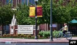 Seorang pengendara sepeda yang mengenakan masker mengendarai sepedanya di University of Southern California (USC) di Los Angeles, California pada 25 Agustus 2020. (Foto: AFP)