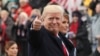 U.S. President Donald Trump points to the stands as he walks with his wife Melania during the Inaugural Parade in Washington, Jan. 20, 2017. 