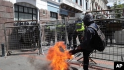 Un manifestante patea una llanta en llamas en una barricada policial que impedía el acceso al Palacio Presidencial en Quito, Ecuador, el 25 de mayo de 2020.