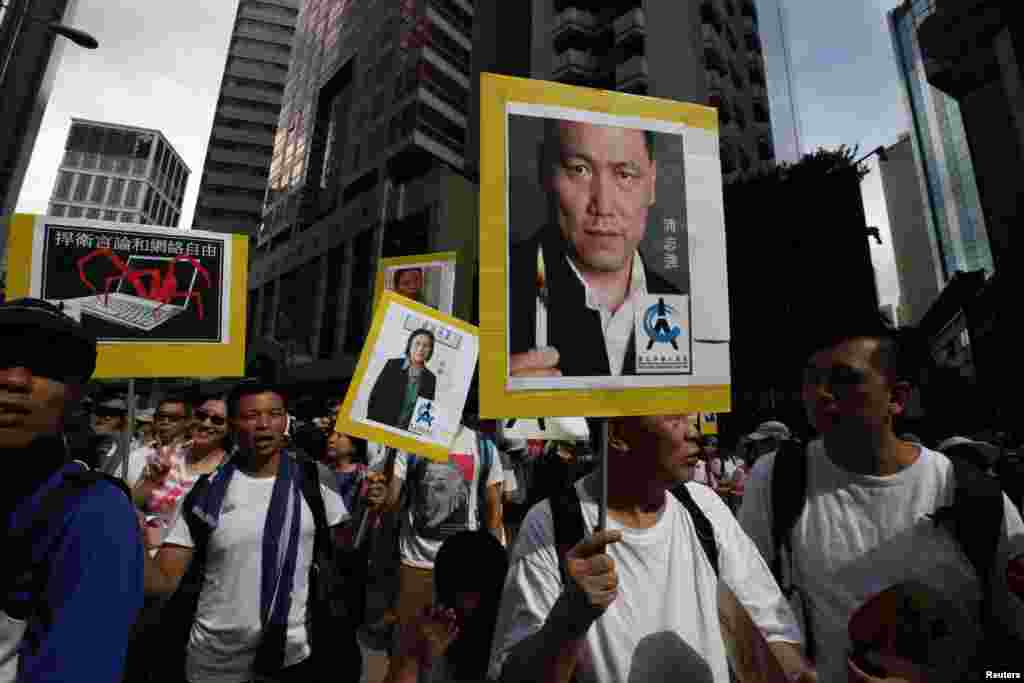 Demokratik islohotlar o&#39;tkazilishini talab qilgan namoyishchilar hibsdagi xitoylik inson huquqlari faoli Pu Zikiang (o&#39;ngda) va jurnalist Gao Yuning suratlarini ko&#39;tarib chiqishdi, 1-iyul, 2014-yil.