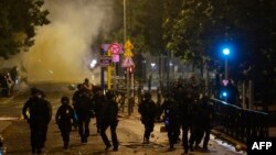 Para polisi anti huru hara berlari selama protes di Nanterre, sebelah barat Paris, pada 28 Juni 2023, sehari setelah pembunuhan seorang remaja berusia 17 tahun, Nahel M., di Nanterre oleh tembakan seorang petugas polisi menyusul penolakan untuk mematuhi perintah.