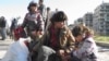 FILE - Syrian children sit with their belongings as they wait to be evacuated from a besieged area of Homs Feb. 12, 2014.
