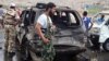 This citizen journalism image provided by Edlib News Network shows Syrian rebels with damaged cars at the scene where a car bomb exploded at a crossing point near Syria's border with Turkey, Sept. 17, 2013.