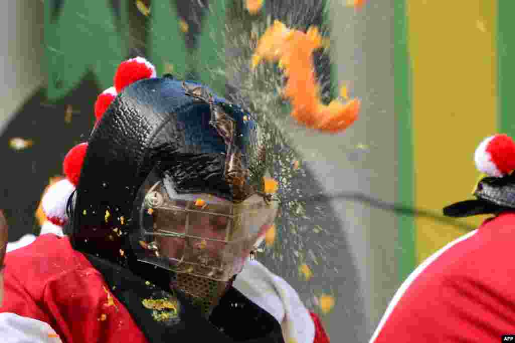 Men with helmets are hit by oranges during the traditional &quot;battle of the oranges&quot; held during the carnival in Ivrea, near Turin, Italy.