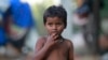 FILE - A child eats a pomegranate collected from waste at a slum area on the outskirts of Jammu, India, Oct. 12, 2018. 
