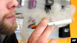FILE - A sales associate demonstrates the use of an electronic cigarette and the smoke-like vapor that comes from it, in Aurora, Colorado, March 2, 2011.