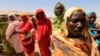 Displaced women wait to receive food at a food distribution center as special envoys and diplomats arrive for a meeting to discuss the progress of a peace treaty in Darfur, at Shangli Tobay village in North Darfur, June 18, 2013.